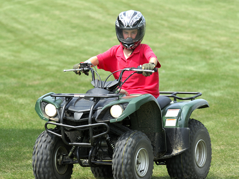 young boy in red shirt riding ATV vehicle